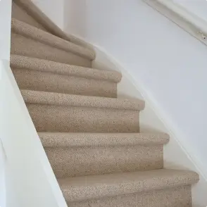 Foto van een gestoffeerde trap met een witte plinten